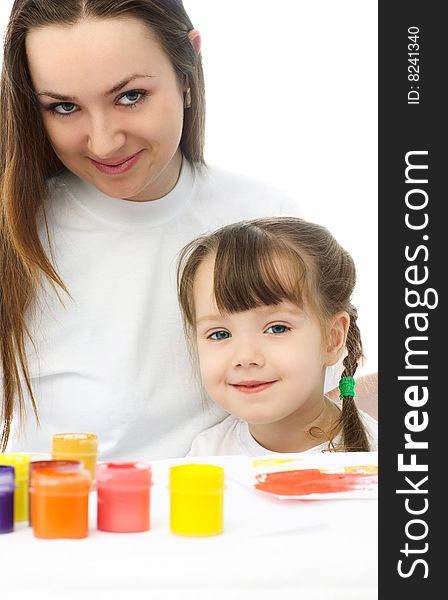 Young mother and her daughter sitting by the table and painting with watercolor. Young mother and her daughter sitting by the table and painting with watercolor