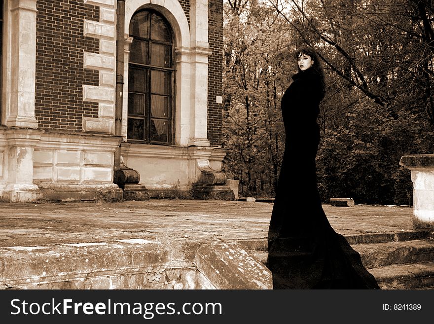 Girl in fall park beside old house in black fabric. Girl in fall park beside old house in black fabric