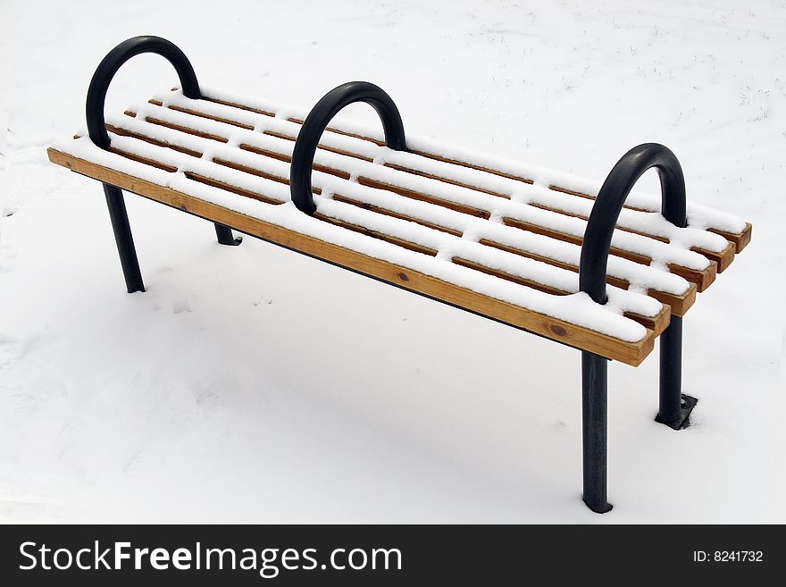 A bench on the snowfield in the park.