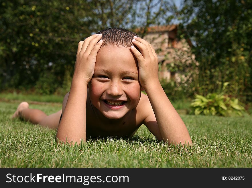Little boy in green grass in hot summertime