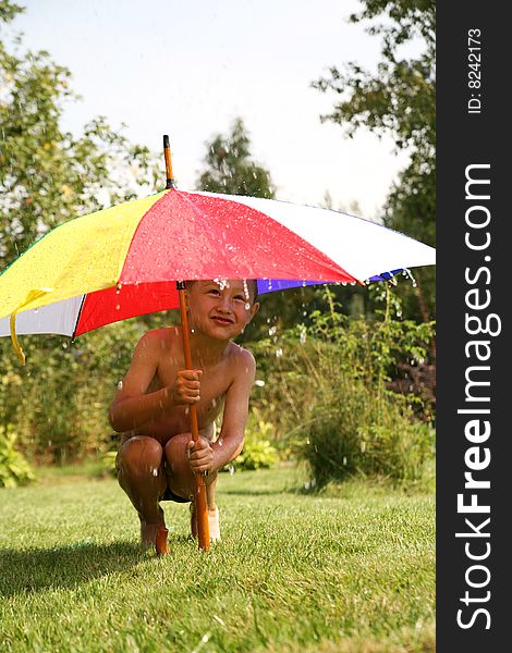 Little boy under umbrella in rain