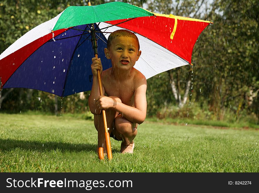 Little boy under umbrella in summer rain