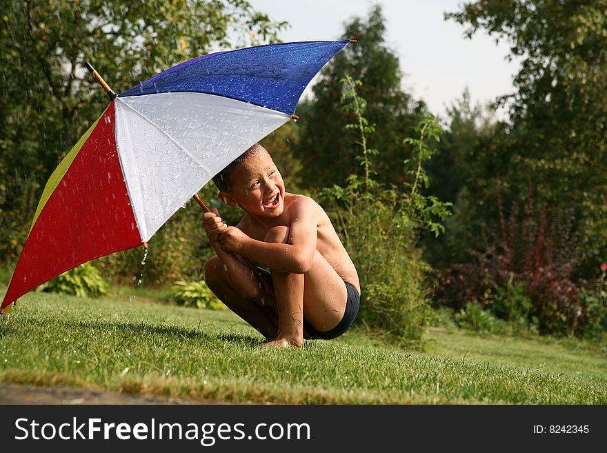 Boy under umbrella in summer rain