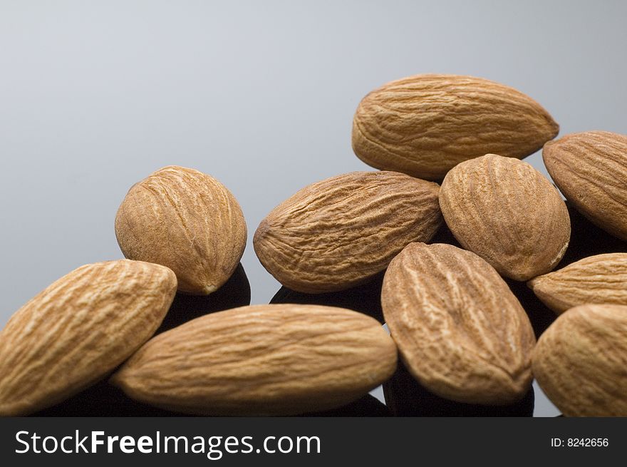 Pile of natural almonds on black reflective background.