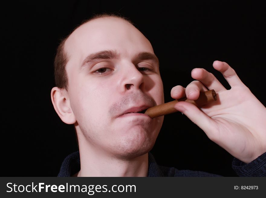 Young man with cigar on black background