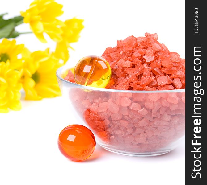 Spa pruducts: bath salt, oil balls in a bowl and yellow flowers