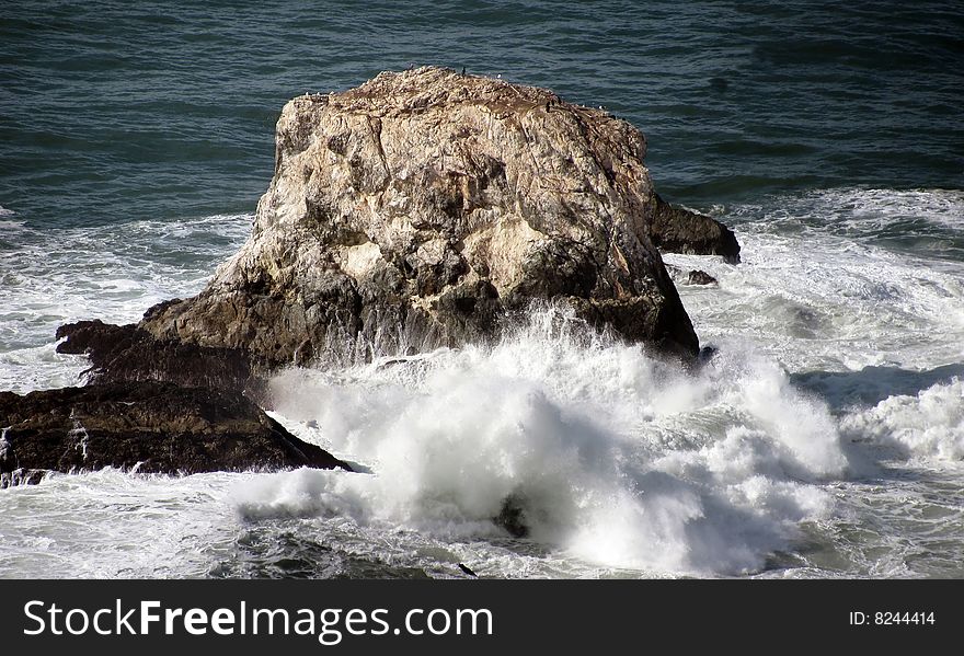A rock, with waves crashing on it and birds ignoring the waves, off the coast of Northern California. A rock, with waves crashing on it and birds ignoring the waves, off the coast of Northern California.