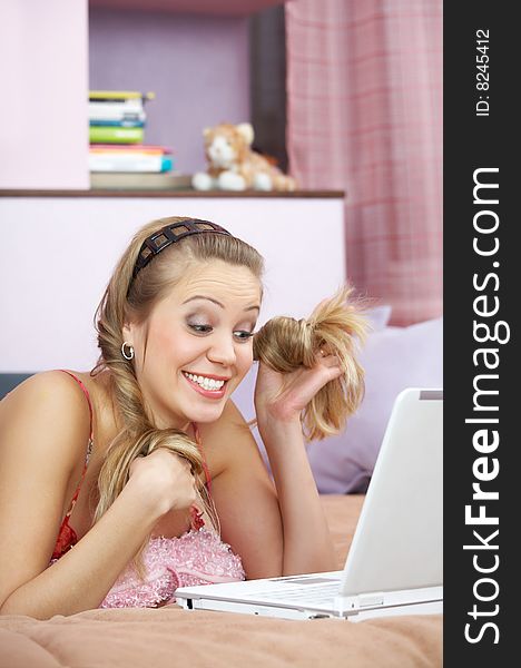The surprised girl plays hair in front of the laptop. The surprised girl plays hair in front of the laptop