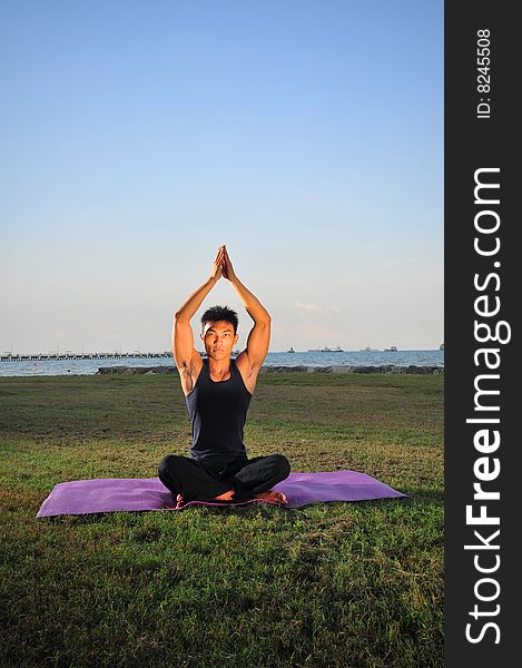 Picture of man doing yoga by the beach.