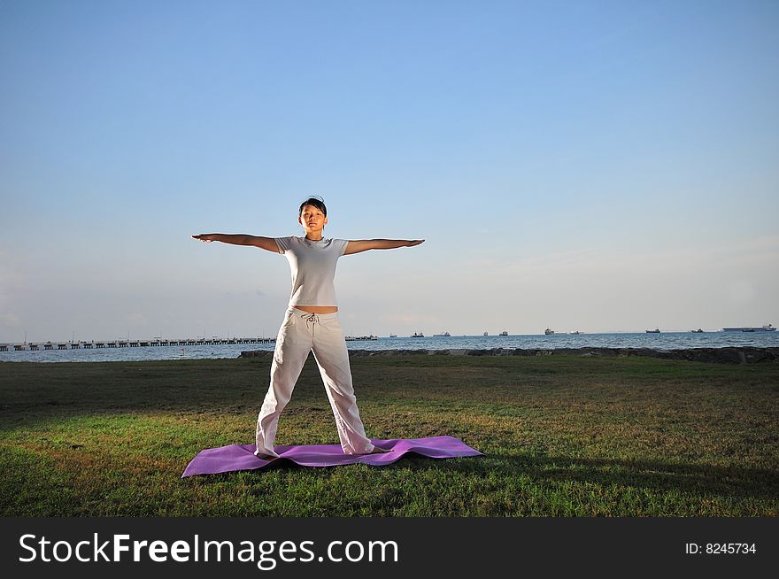 Picture of a woman doing yoga by the beach.