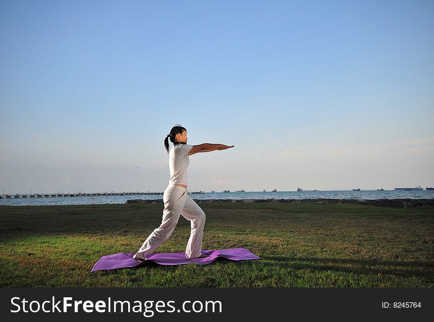 Picture of a woman doing yoga by the beach.