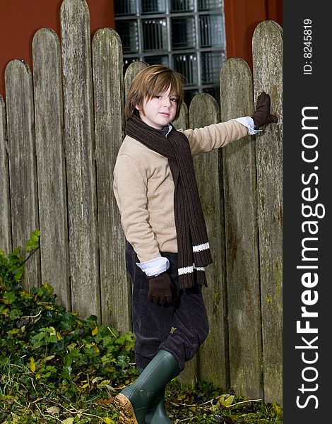 Cute young autumn boy standing near a fence. Cute young autumn boy standing near a fence