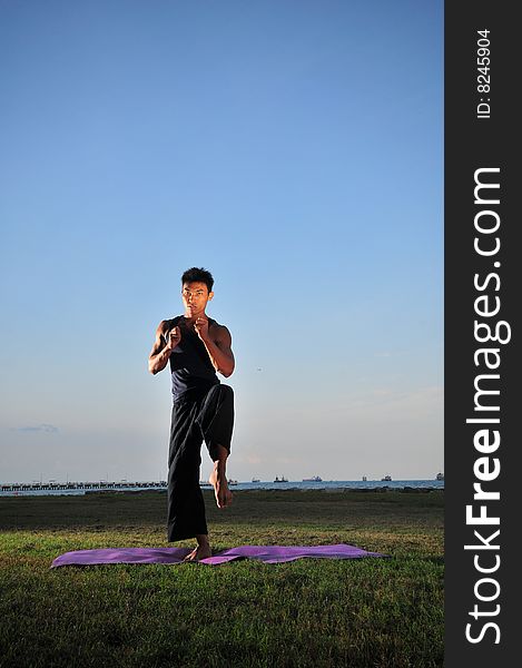 Picture of man doing yoga by the beach.
