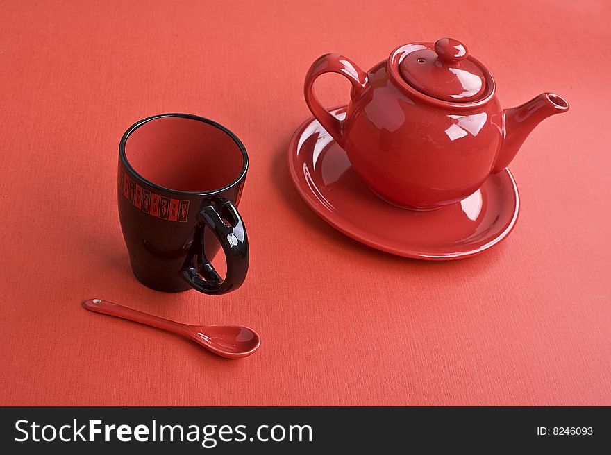 Teapot, cup and spoon on red table. Teapot, cup and spoon on red table
