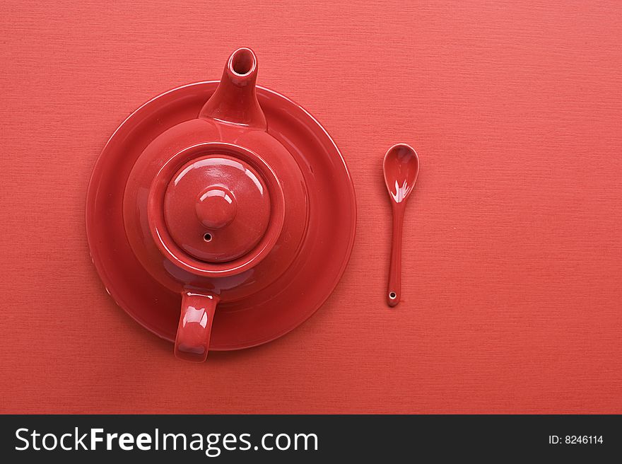 Teapot, cup and spoon on red table. Teapot, cup and spoon on red table