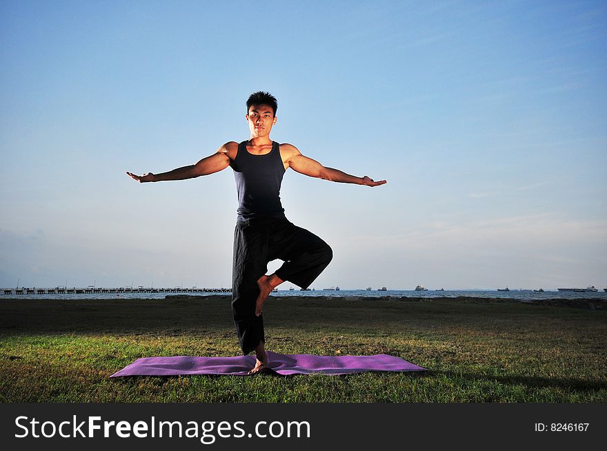 Picture of man doing yoga by the beach.