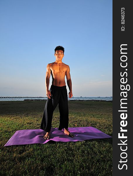 Picture of man doing yoga by the beach.
