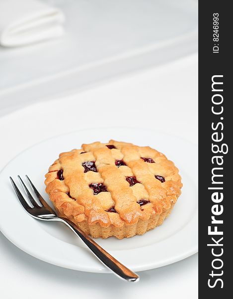 Small cherry pie on white saucer with fork