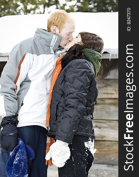 A young couple kisses in the snow. A young couple kisses in the snow.