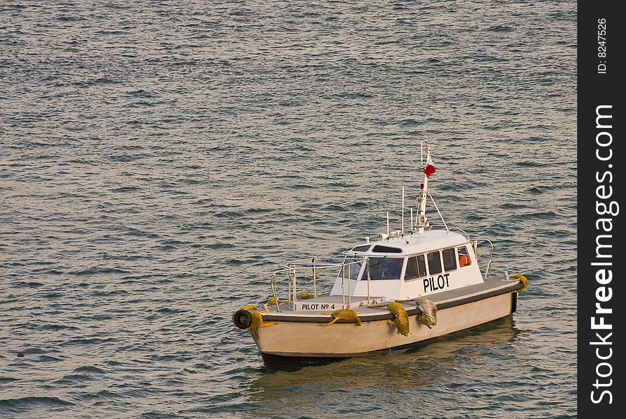 An old pilot boat in calm water in a bay. An old pilot boat in calm water in a bay