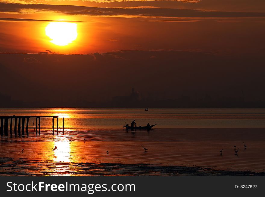 Fisherman sailing under golden sunrise at the coastal.