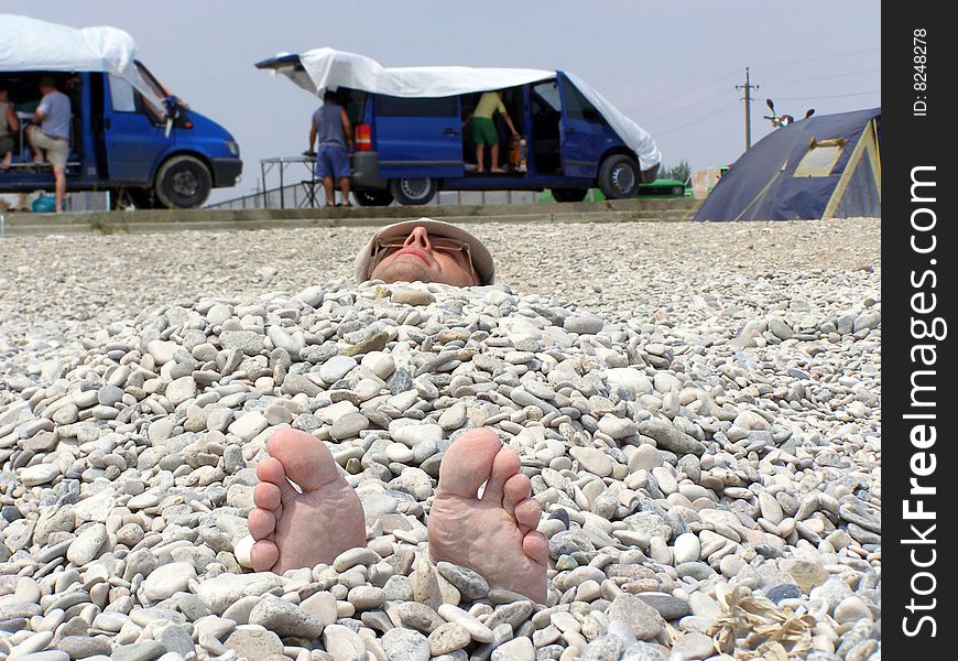 The man lays and has a rest under stones. The man lays and has a rest under stones