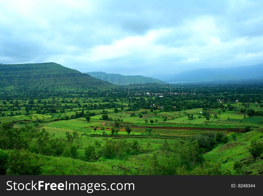 A beautiful landscape scene with vibrant green fields and distant mountain. A beautiful landscape scene with vibrant green fields and distant mountain.