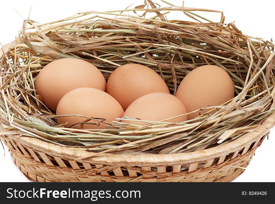 Chicken eggs in the brown basket and hay.