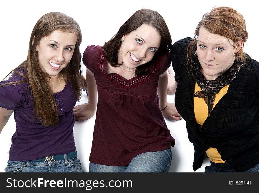 Three young women sitting together and smiling. Three young women sitting together and smiling.