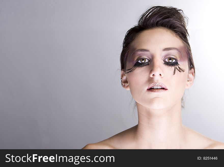 Attractive young lady with extravegant makeup and eyelashes plain background