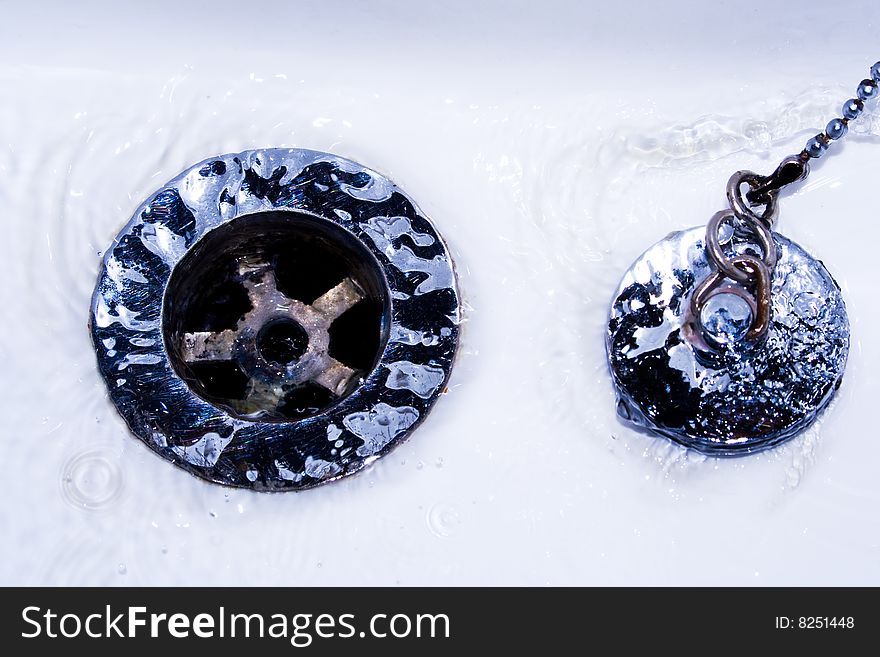 Sink and silver plug with water draining. Sink and silver plug with water draining