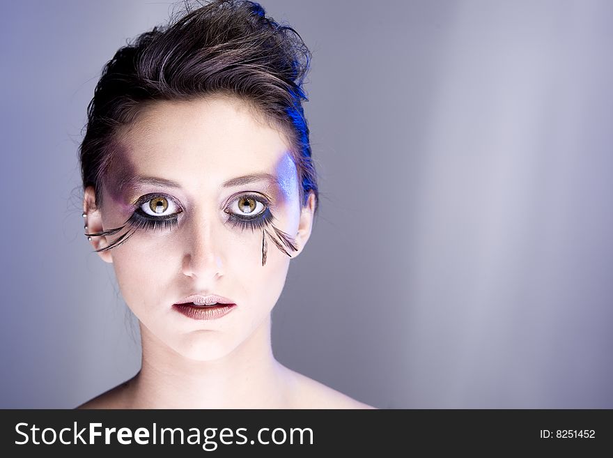 Attractive young lady with extravegant makeup and eyelashes with plain background