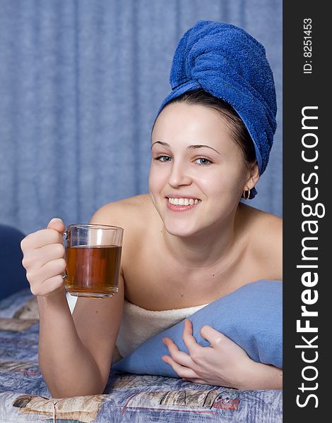 Beautiful girl in dark blue towel with cup in hand