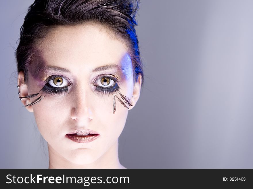 Attractive young lady with extravegant makeup and eyelashes close up of face