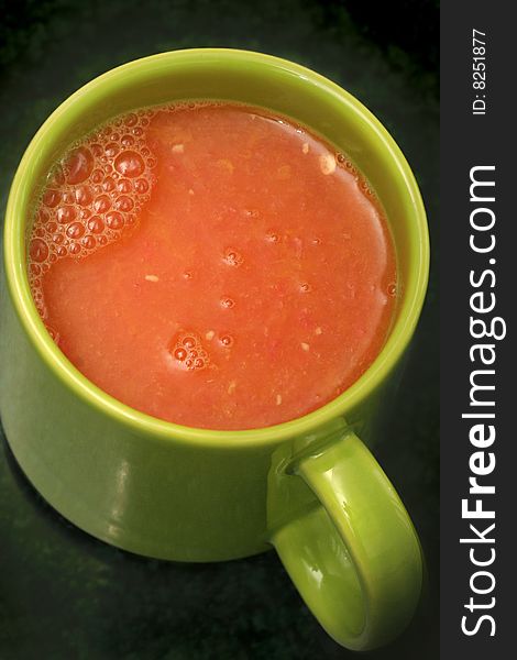 Fresh orange and grapefruit juice in a green cup. Fresh orange and grapefruit juice in a green cup