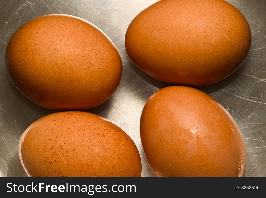 Four brown eggs on scratched metallic surface