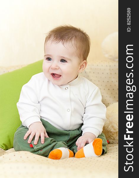 Portrait of adorable happy blue-eyes baby sitting on sofa. Portrait of adorable happy blue-eyes baby sitting on sofa