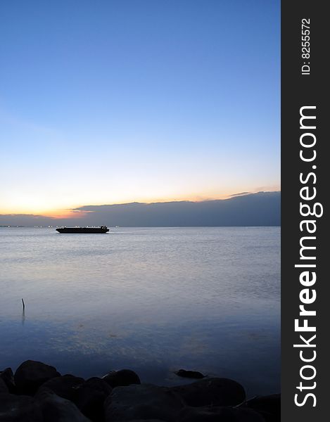 A barge left out near the shore silhouetted by the bay sunset. A barge left out near the shore silhouetted by the bay sunset.