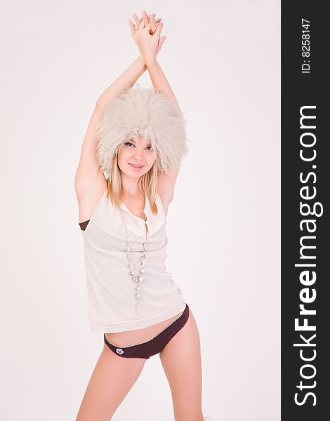 Young girl in furry hat rising her hands up, studio shot