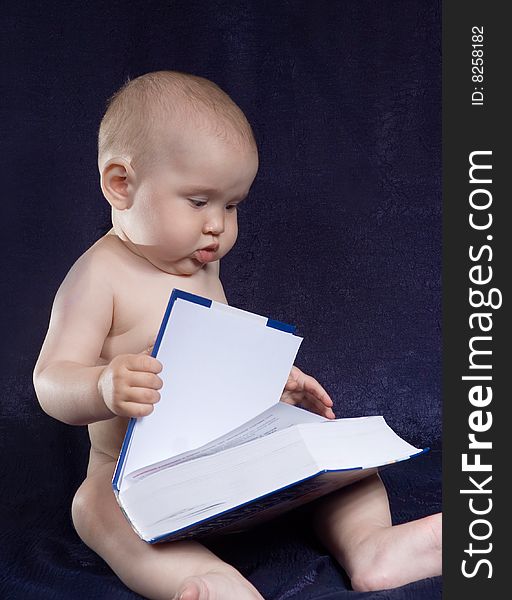 Child sits with book on turn blue background. Child sits with book on turn blue background