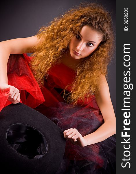 Red-haired girl holding hat over dark background