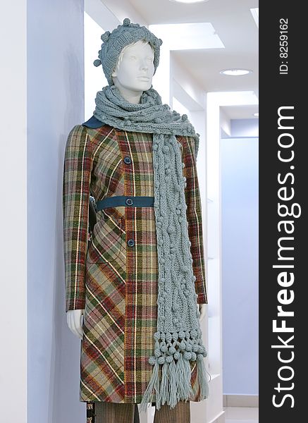 Dummy in the checkered coat, wool knitted hat with scarf, trousers. Dummy in the checkered coat, wool knitted hat with scarf, trousers