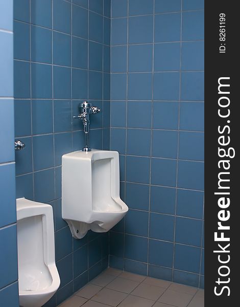 Urinals in the men's room with blue tiles on the wall