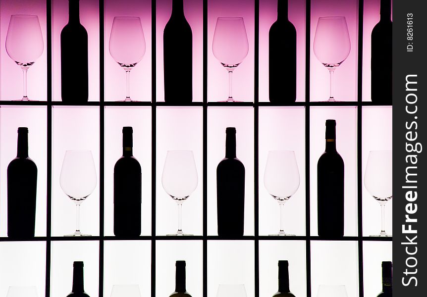 Black bottles and crystal glasses decorate a wall creating a motif