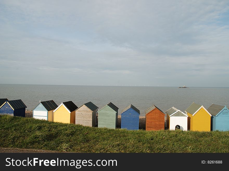 Beach huts with wind turbines on the horizon