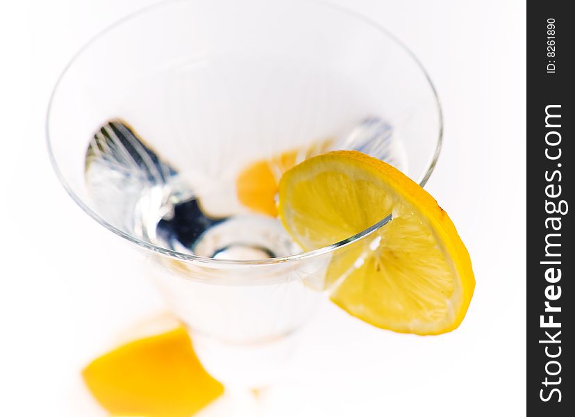 Transparent glass with a liquid, a segment of a lemon and the cut lemon at the glass basis. Transparent glass with a liquid, a segment of a lemon and the cut lemon at the glass basis.