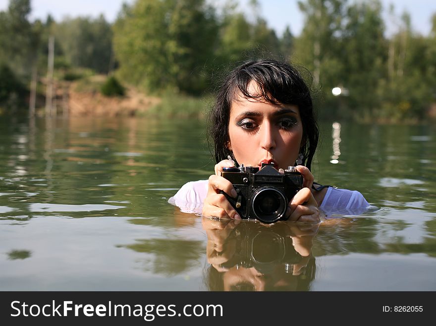 Lovely girl photographer in water in summertime