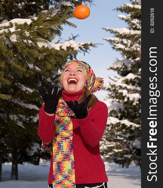 Girl throws orange amongst fir trees