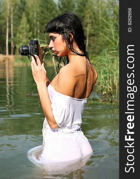 Lovely brunette girl photographer in water in hot summertime