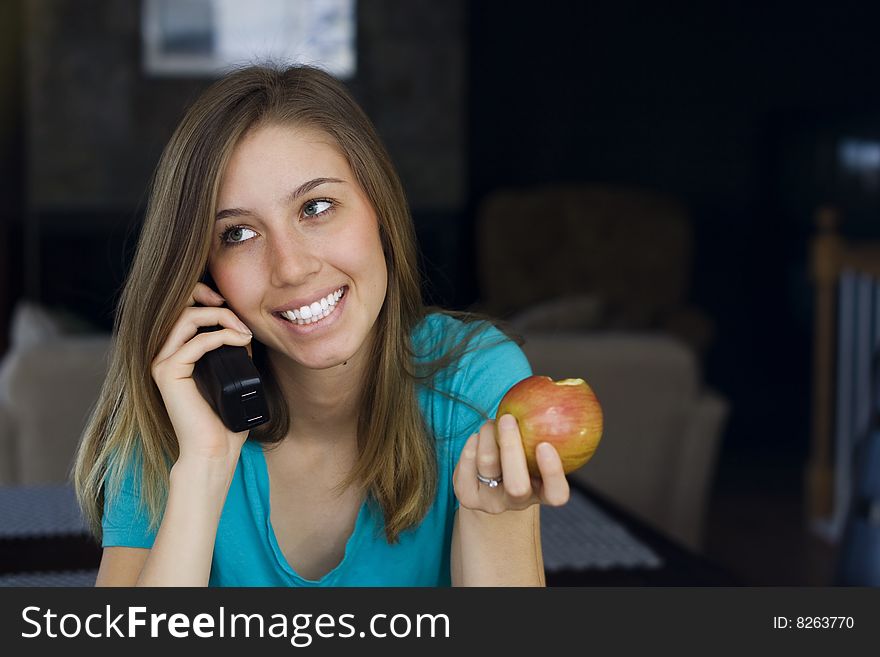 Beautiful young woman talks on the telephone while eating an apple at home. Beautiful young woman talks on the telephone while eating an apple at home.